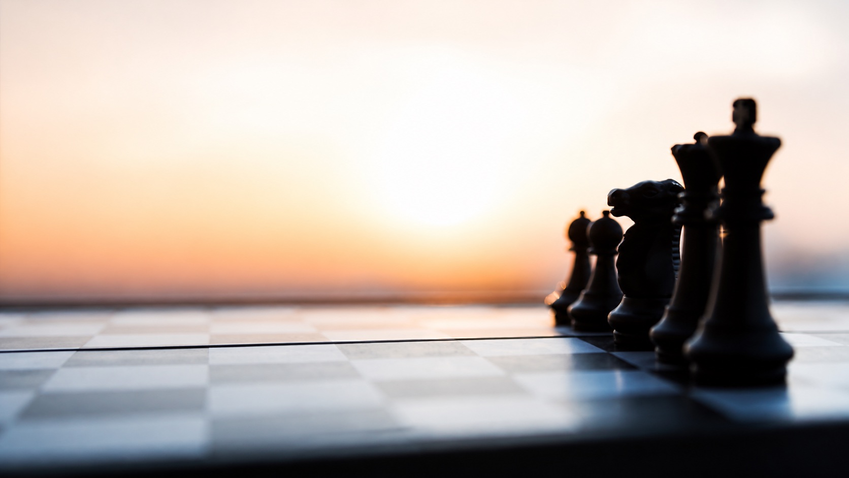 Chess pieces arranged on a board at sunrise